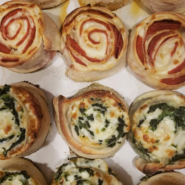 A close-up of Sayville Pizza's pepperoni and spinach pinwheels, golden brown and cheesy.