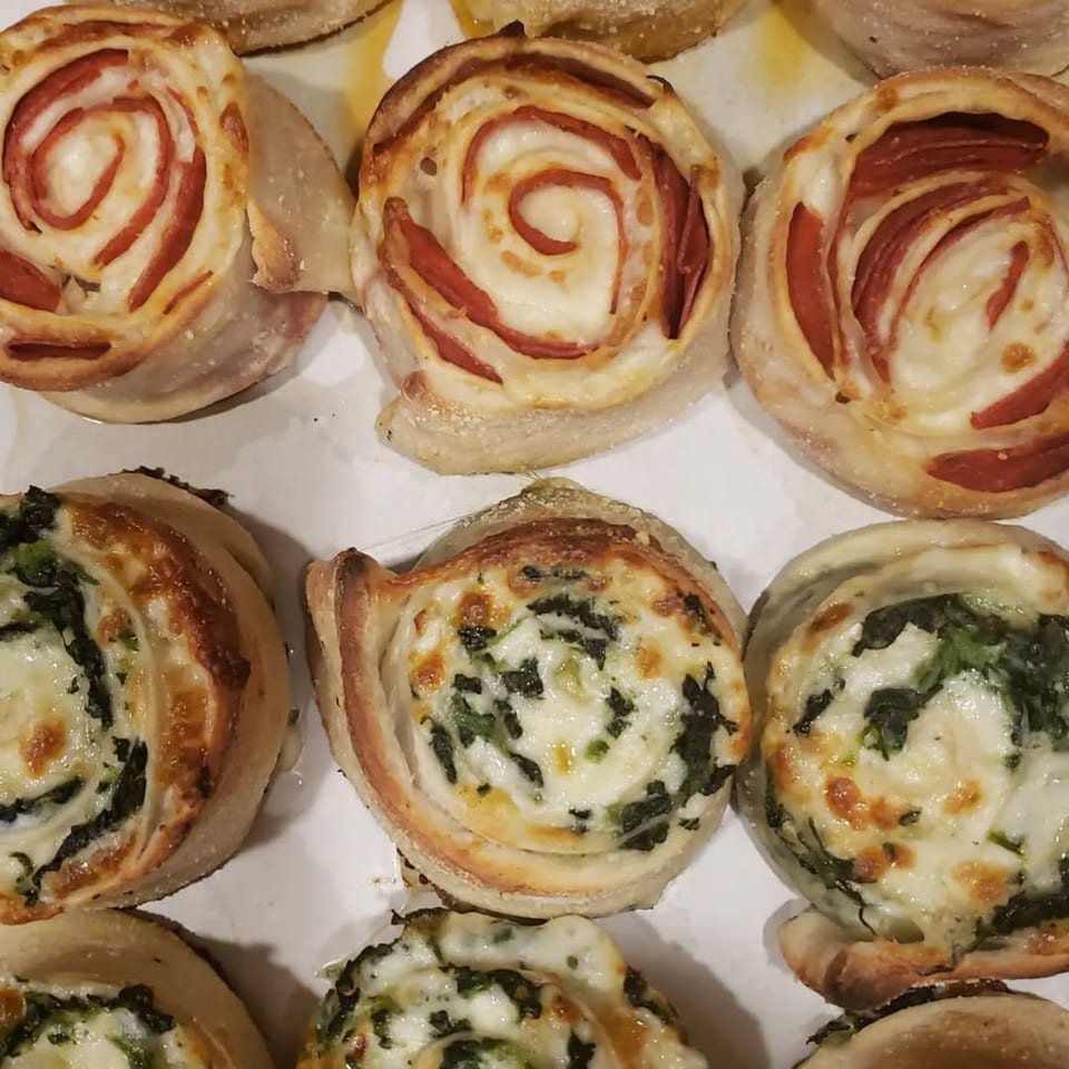 A close-up of Sayville Pizza's pepperoni and spinach pinwheels, golden brown and cheesy.